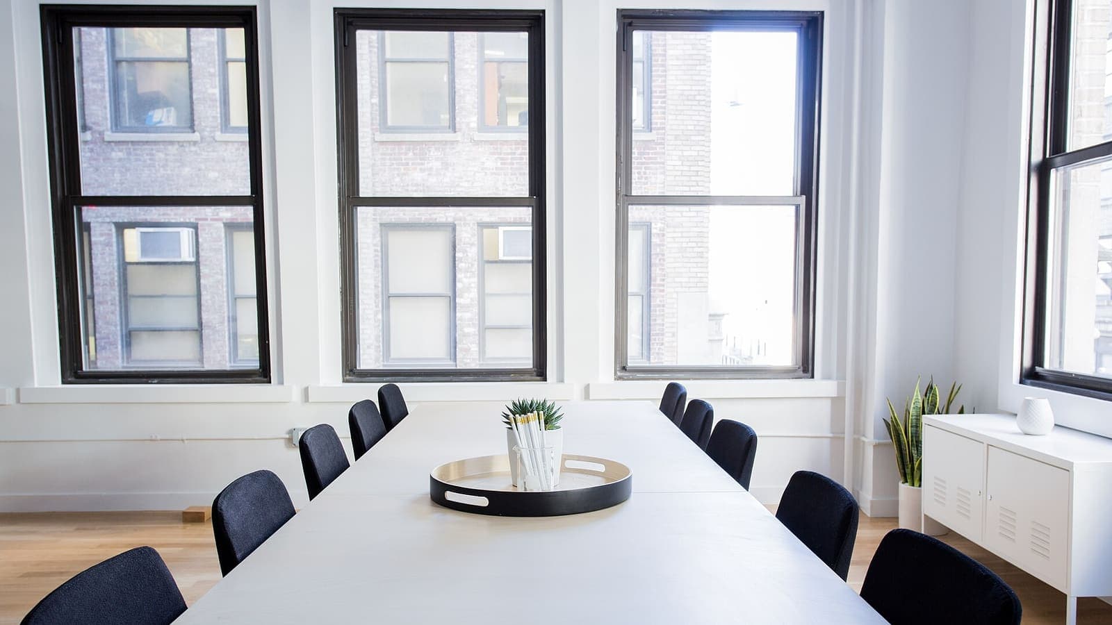 Lege, lichte vergaderruimte met een lange witte tafel en zwarte stoelen